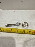 Both watches side by side with measuring tape for scale