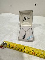 Necklace in open Stars box with measuring tape for scale