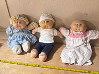 All three dolls lined up on table with measuring tape
