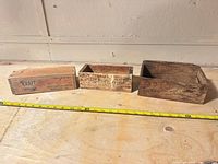 Three wooden cheese boxes side by side with measuring tape