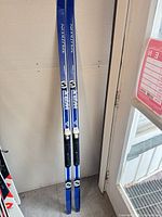 Full view of the pair of blue Splitkein skis leaning against wall, bindings visible