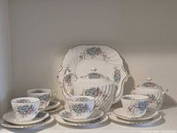 Full tea set displayed: teapot, sugar bowl, teacups, saucers, side plates, cake plate