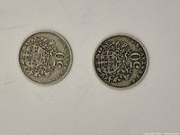 Obverse view of both coins showing coat-of-arms within wreath and denomination