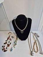 Overall lot showing six necklaces on display bust and table