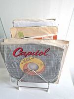 Stack of 7" singles on wire stand showing Capitol sleeve