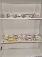Two shelves showing majority of the teacup and saucer sets neatly arranged