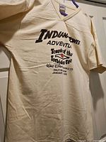 Full view of cream V-neck T-shirt hanging, showing overall condition and size