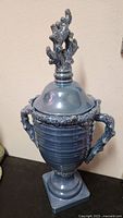 Full view of blue ceramic urn with lid showing handles and base