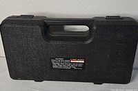 Closed black case front view with label