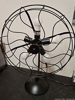 Front view of black industrial fan lamp showing cage, bulb sockets, and base