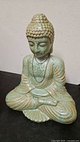Front view of green crackle-glazed ceramic kneeling Buddha statue