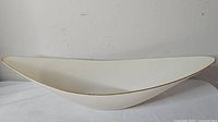Side view of ivory Lenox oval bowl with gold rim