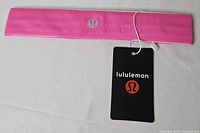 Pink Lululemon headband laid flat showing logo and tag