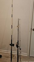 Both rod and reel combinations standing upright against wall