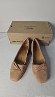 Front view of pair of nude leather & suede Clarks flats with original box behind