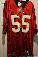 Full front view of red Reebok #55 jersey hanging with tags visible