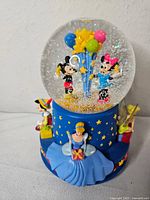 Front view of Disney 100 musical snowglobe showing Mickey, Minnie, Cinderella, Pinocchio, Tinker Bell
