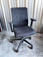Front view of black fabric rolling office chair showing seat, back, base and casters