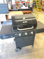 Full view of Char-Broil three-burner gas grill on cart showing side shelves and wheels