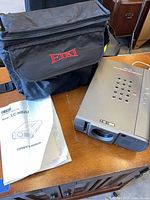 Projector with carrying case and manual on table