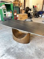 Overall view of table showing matte black top and curved pedestal base