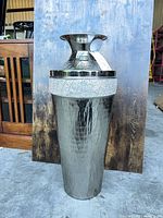 Full view of tall hammered metal vase showing overall shape and finish