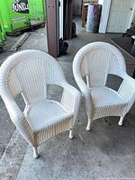 Two white wicker armchairs side by side
