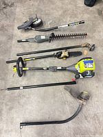 All components laid out: powerhead, four attachments, two shafts, strap