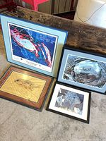 All four framed artworks leaning against wall showing variety in size and frame color