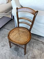 Front angled view of wood ladder-back chair showing cane seat and turned legs