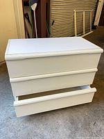 Front view showing three drawers, bottom drawer partially open