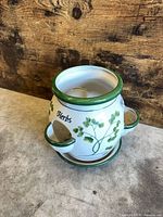 Front view of white porcelain herb planter showing two side pockets, green rim, herb print, matching saucer