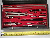 Open case showing all 14 drafting instruments in red velvet interior