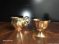 Front view of creamer and sugar bowl showing gold lustre finish