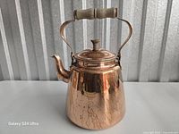 Front view of copper teapot showing body, spout, handle and lid