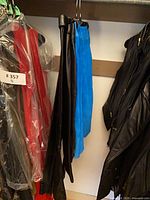 Group of black faux-leather garments and blue pencil skirt hanging on closet rod