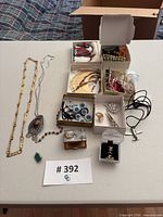 Overview of entire lot laid on table showing necklaces, rings, bracelets, boxed items