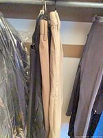 Two pairs of pants hanging in closet (black pair present but seller states khaki pair only)