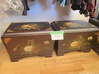 Two painted wood trunks side by side showing floral designs and hardware