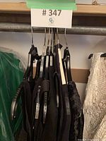 Group of black dresses on hangers under lot tag