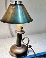 Front view of antique brass lamp showing shade, column, base and cord