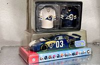 Lot overview showing boxed Rams jersey salt & pepper shakers atop sealed #03 Rams die-cast car