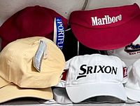 Front view showing Marlboro visor, Srixon cap, beige blank cap, red cap, partial white cap