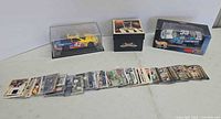 Overview of football trading cards laid out in row; Revell #42 car in display case; Hot Wheels #33 car box visible