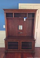 Full front view of Ethan Allen entertainment center showing upper shelf, back panel cutout, and lower glass-door cabinet