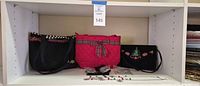 Shelf view showing three handbags and jewellery packets