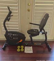 Full view of bike, dumbbells and manual