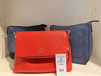 All three handbags front view: red Kate Spade, two navy bags
