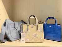 All three handbags side by side on shelf