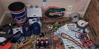 Entire lot laid out including wastebasket, hats, clothing, drinkware, plush mascot, wood items and accessories